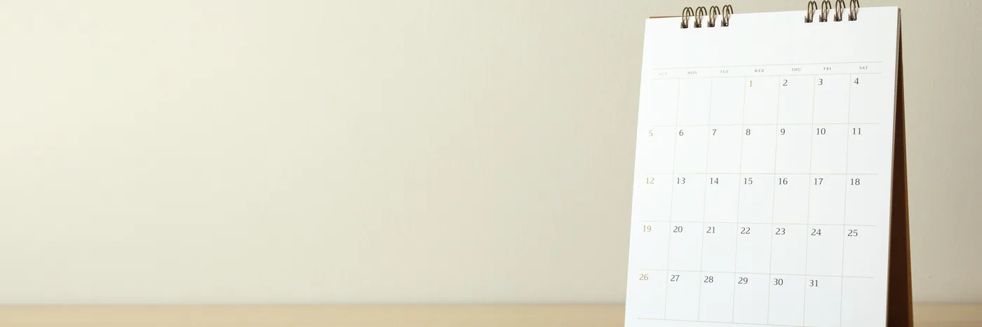A blank desk calendar standing on a wooden table, its month grid empty.